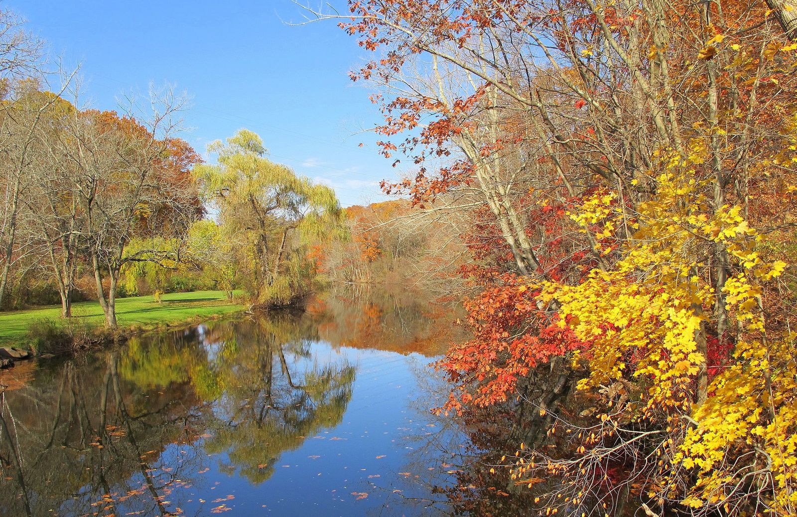 The Quinnipiac River in autumn, lined with red and yellow trees reflected in still water